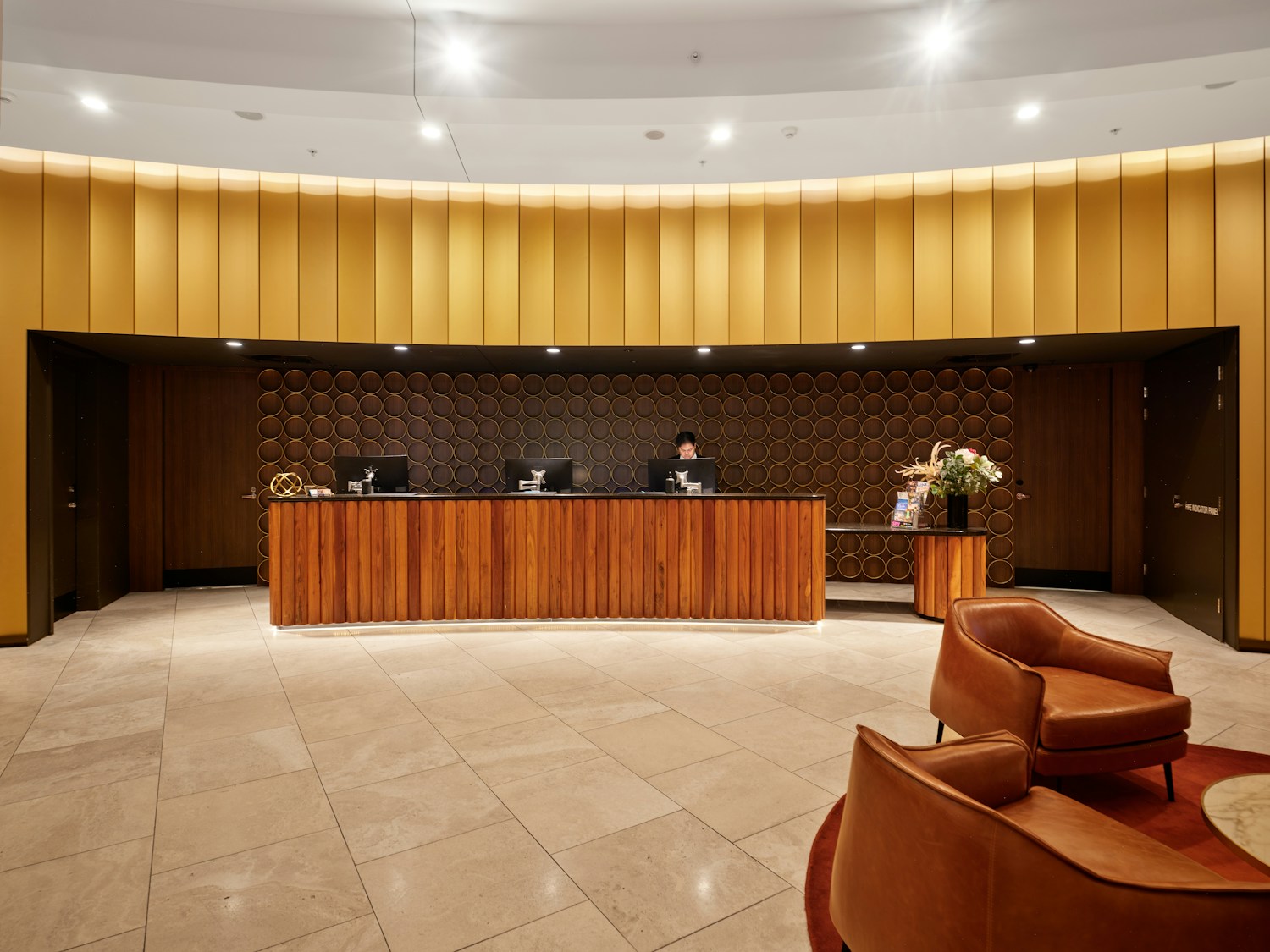 Firmenhotel buchen – Hotelrezeption in warmen Gold- und Holztönen