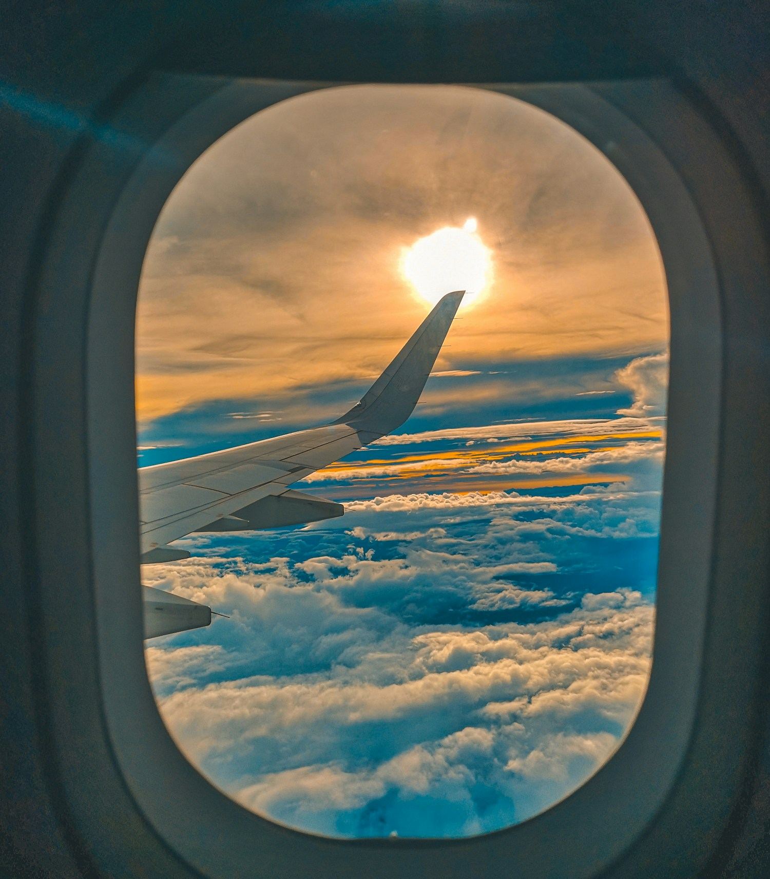 Geschäftsreise ins Ausland – Blick aus dem Flugzeugfenster über den Wolken